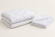 The folded white protector beside a quilted topper on a pale ground. Rendering, not a photograph of shipped goods.
