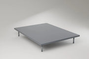 The adjustable base lying flat on slim metal legs, on a pale studio ground. Rendering, not a photograph of shipped goods.