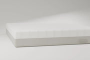 Side profile of the hybrid mattress: quilted ivory cover over a grey knit gusset, on a pale studio ground. Rendering, not a photograph of shipped goods.