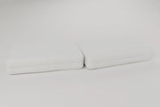 Two foam pillows side by side on a pale studio ground. Rendering, not a photograph of shipped goods.